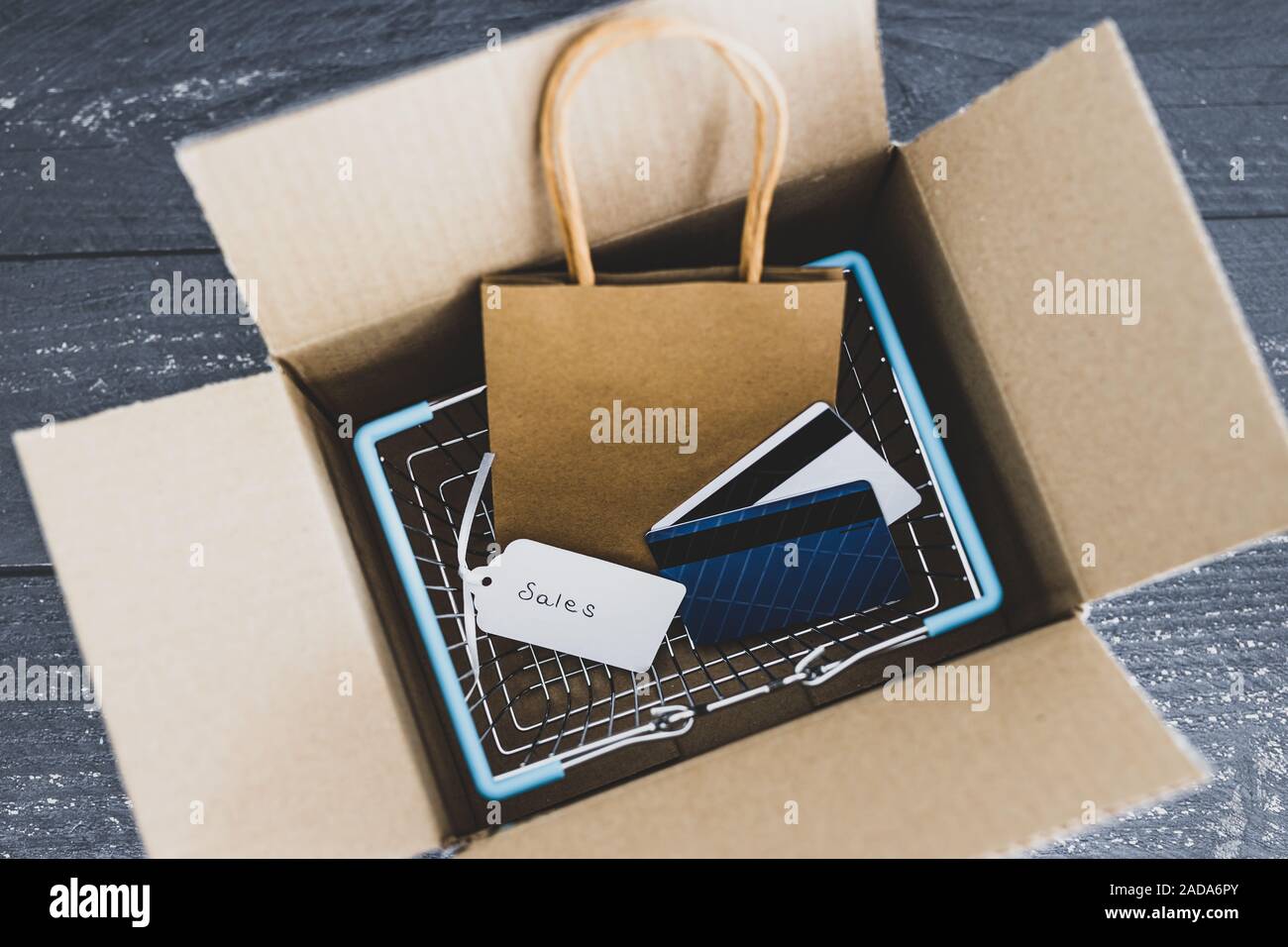 Ordini online conceptual still-life, Shopping basket all'interno di aprire il pacco di consegna con il prezzo di vendita dei tag e carte di pagamento Foto Stock