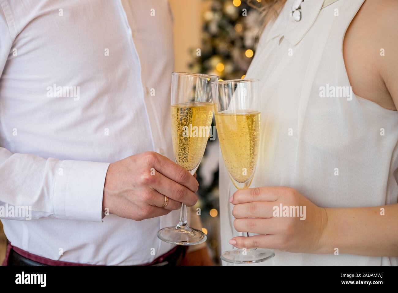 Giovane uomo e donna in eleganti vestiti di vacanza con bicchieri di  champagne in mano in previsione del nuovo anno di vacanza Foto stock - Alamy