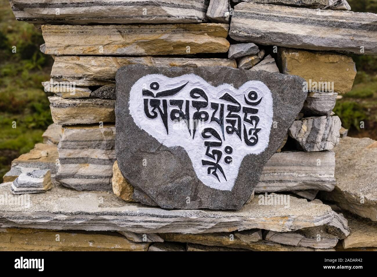 Mani di pietra con inciso il mantra tibetano OM MANI PADME HUM, situato all'entrata del villaggio Foto Stock