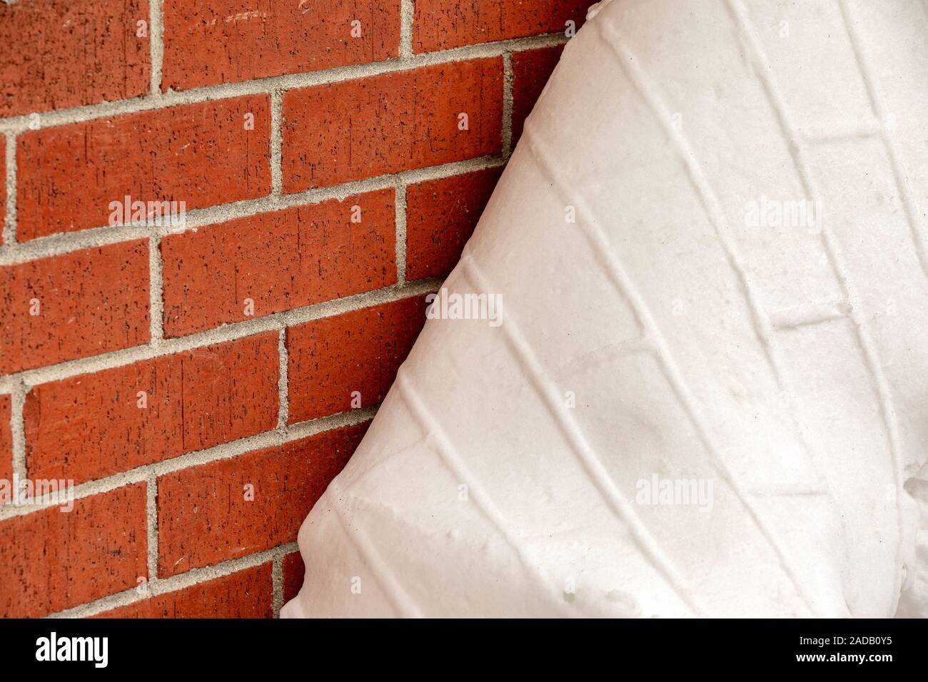 Foglio di neve staccando dal muro di mattoni con una impronta del muro di mattoni di texture. Golden, Colorado, STATI UNITI D'AMERICA Foto Stock