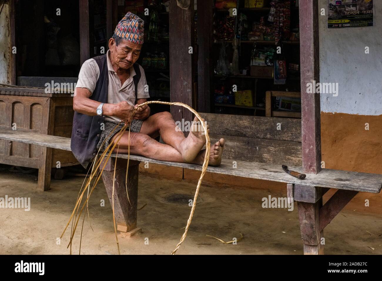 Un vecchio uomo, seduta su una panchina, è un intreccio di un cablaggio da fette di bambù Foto Stock