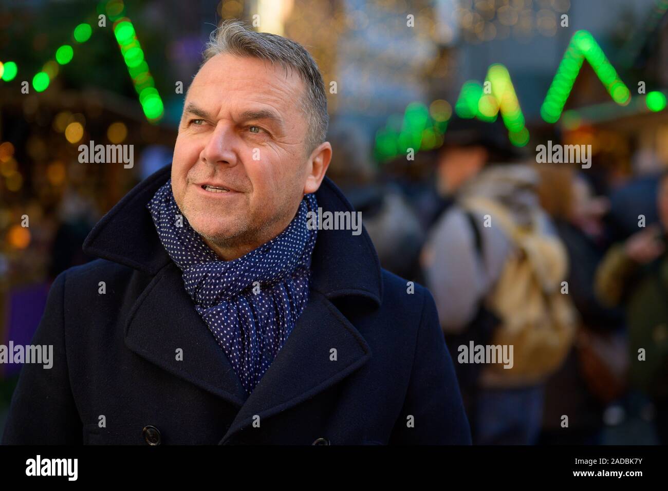 Grave elegante uomo di mezza età in abito invernale in piedi in una piazza urbana e guardando in alto Foto Stock