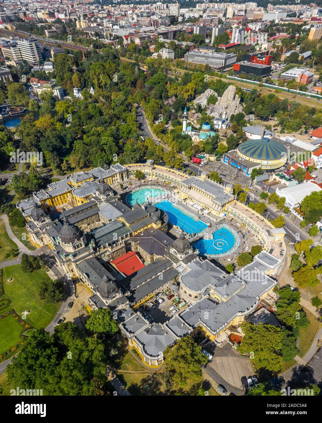 Budapest, Ungheria - Aerial drone vista del famoso Szechenyi bagno termale nel parco cittadino (Varosliget) con lo Zoo di Budapest e capitale circo di Budapest Foto Stock