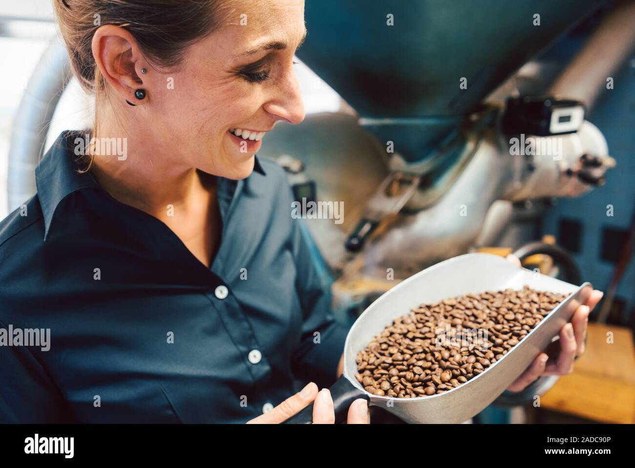 Donna in coffee roastery con chicchi freschi Foto Stock