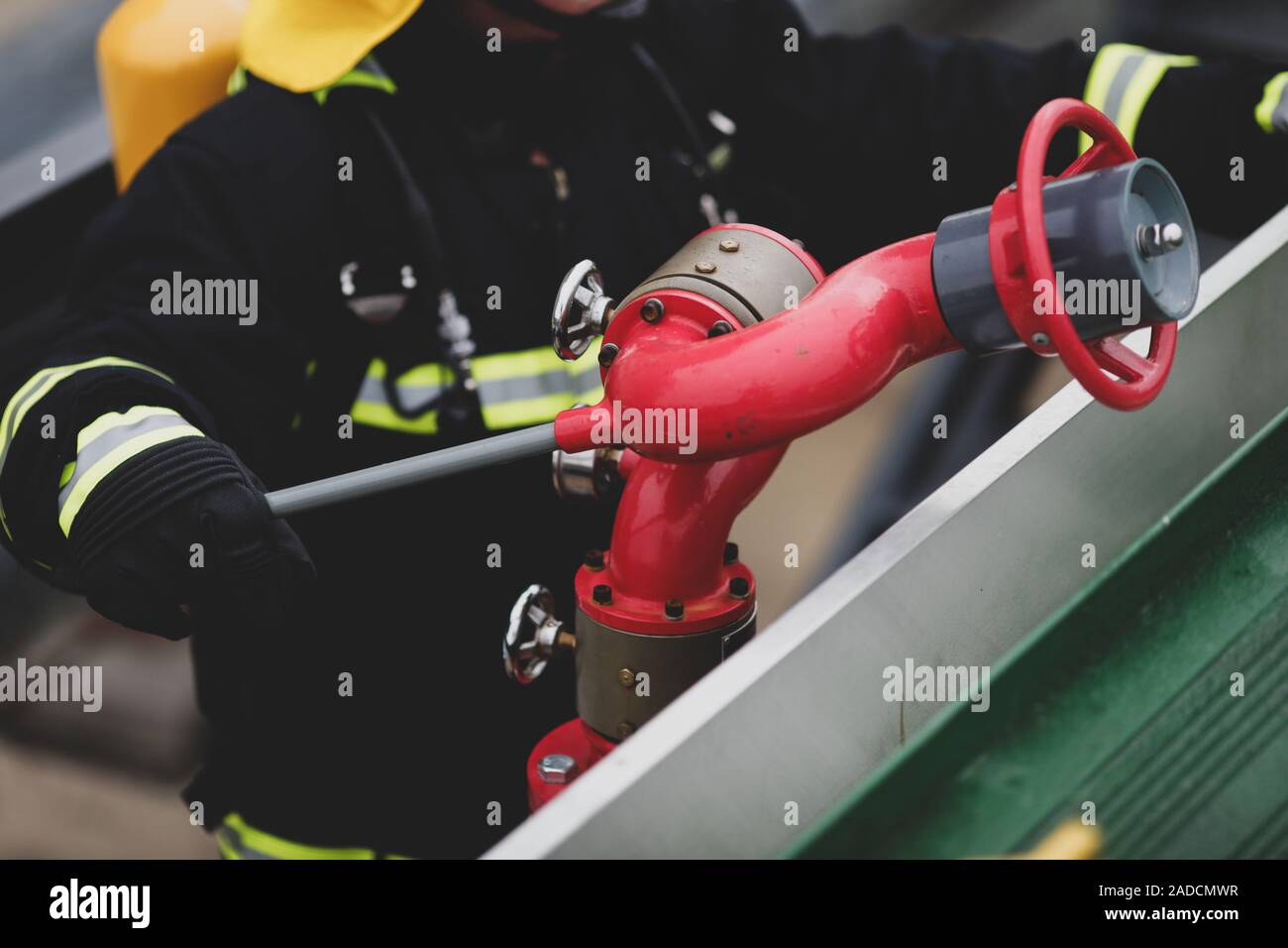 Dettagli con le mani di un vigile del fuoco in possesso di un sistema antincendio idranti () su un ospedale helipad. Foto Stock