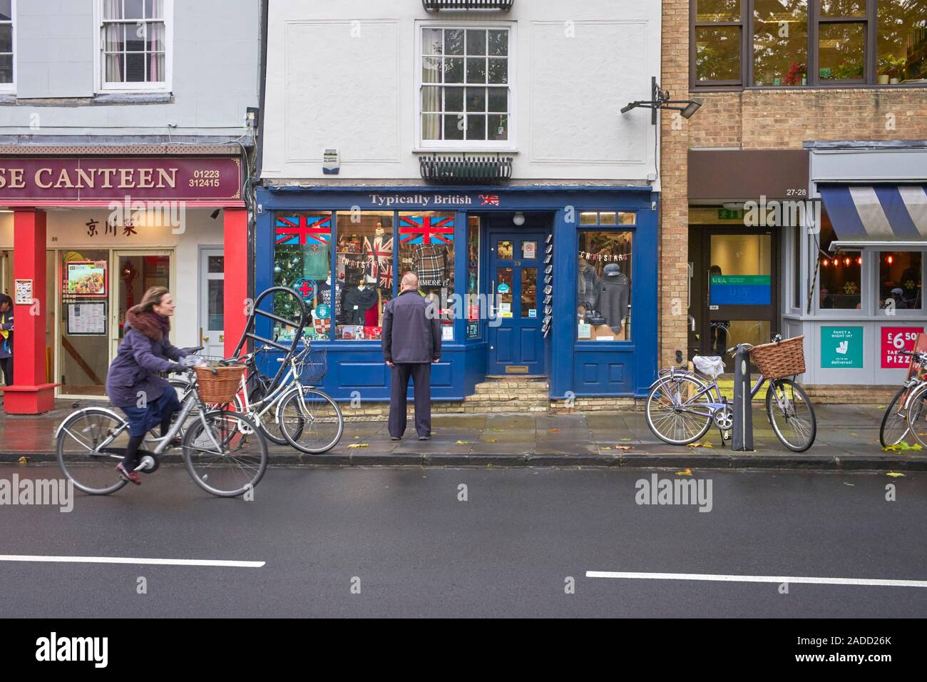 Un vecchio turistici cinesi guardando la finestra di tipicamente britannico shop in Cambridge Foto Stock