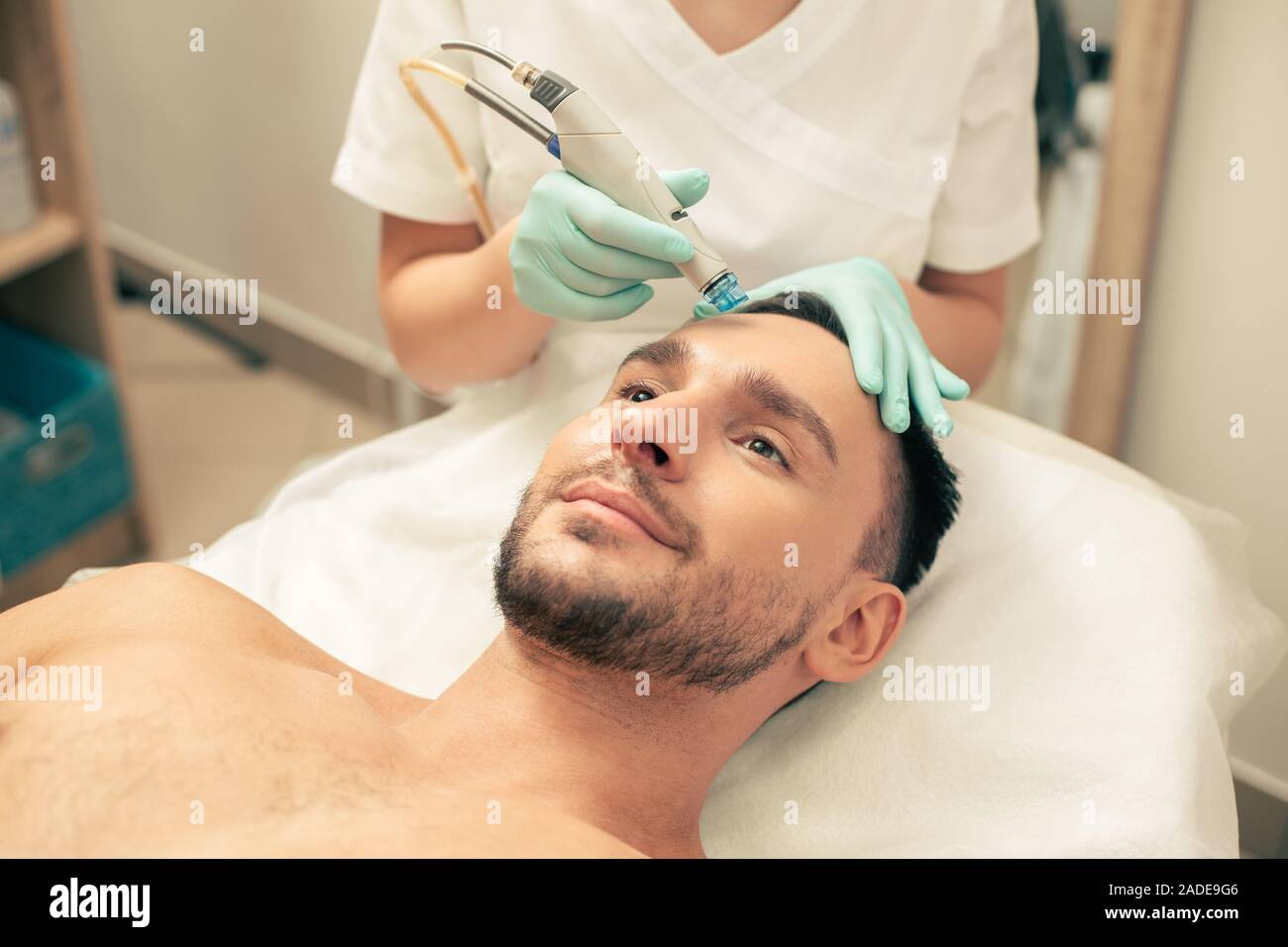 Mano nei guanti di gomma che nutre la pelle dell uomo Foto Stock