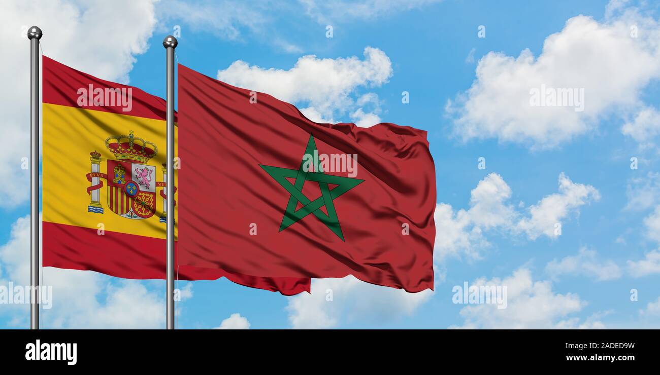 La Spagna e il Marocco bandiera sventolare nel vento contro bianco torbido cielo blu insieme. Concetto di Diplomazia e relazioni internazionali. Foto Stock