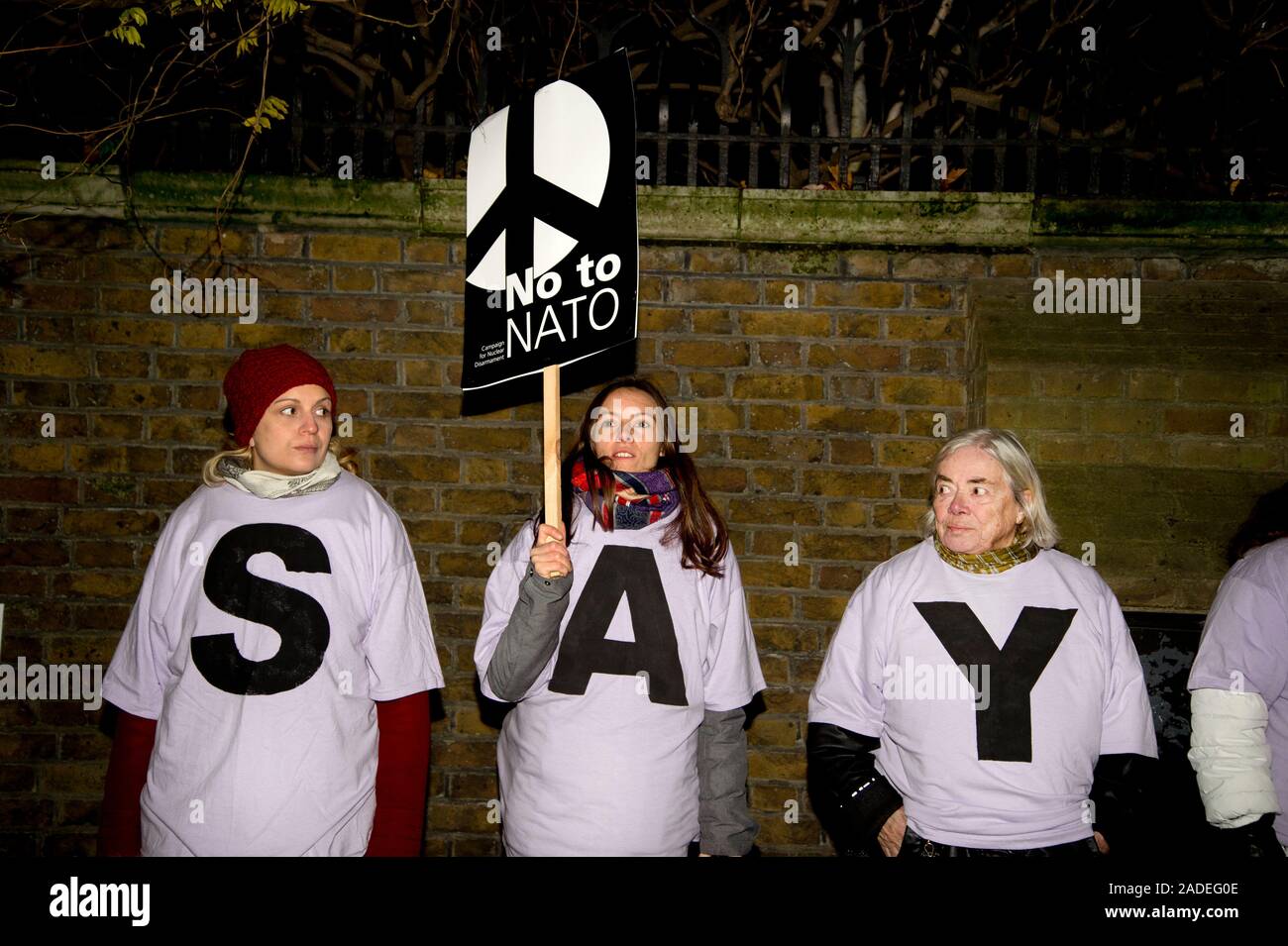 3 dicembre 2019 Trafalgar Square. Anti Trump dimostrazione. Tre donne indossare le magliette bianco ortografia 'say' e un cartello con un simbolo CND e 'n. t Foto Stock