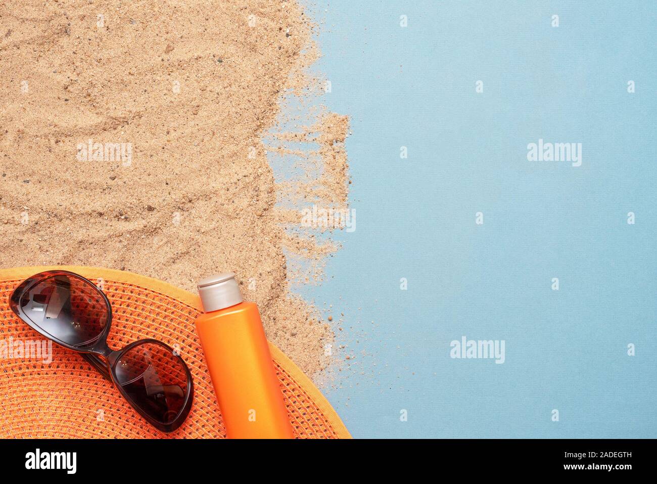 Accessori da spiaggia sulla sabbia su sfondo blu con una copia dello spazio. La vacanza estiva concetto. Foto Stock