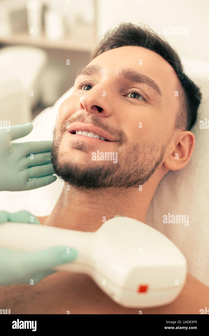 Procedure per il viso sulla pelle del giovane uomo allegro Foto Stock
