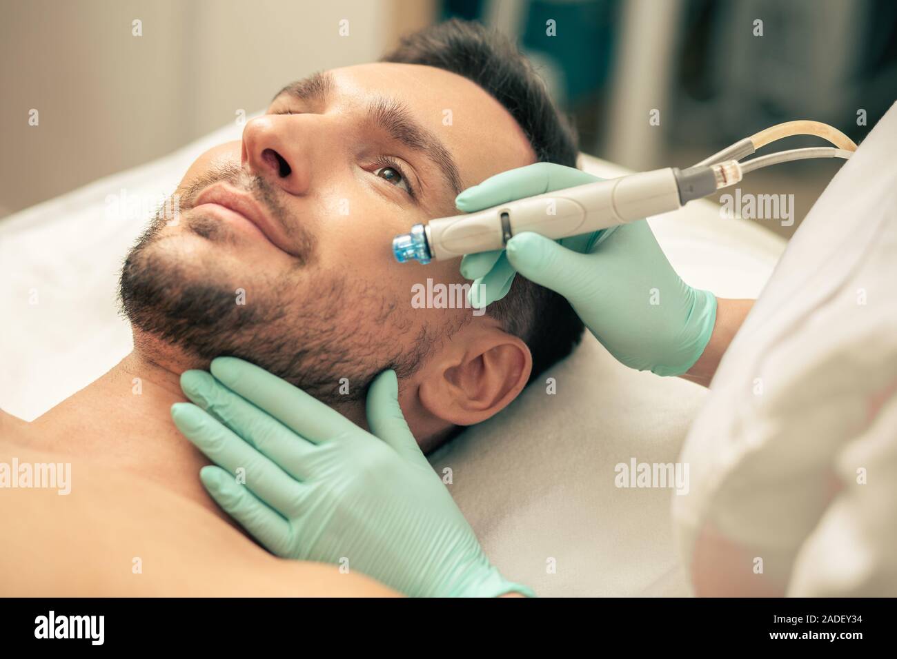 Giovane uomo cercando la calma durante la semplice procedura di pelle Foto Stock