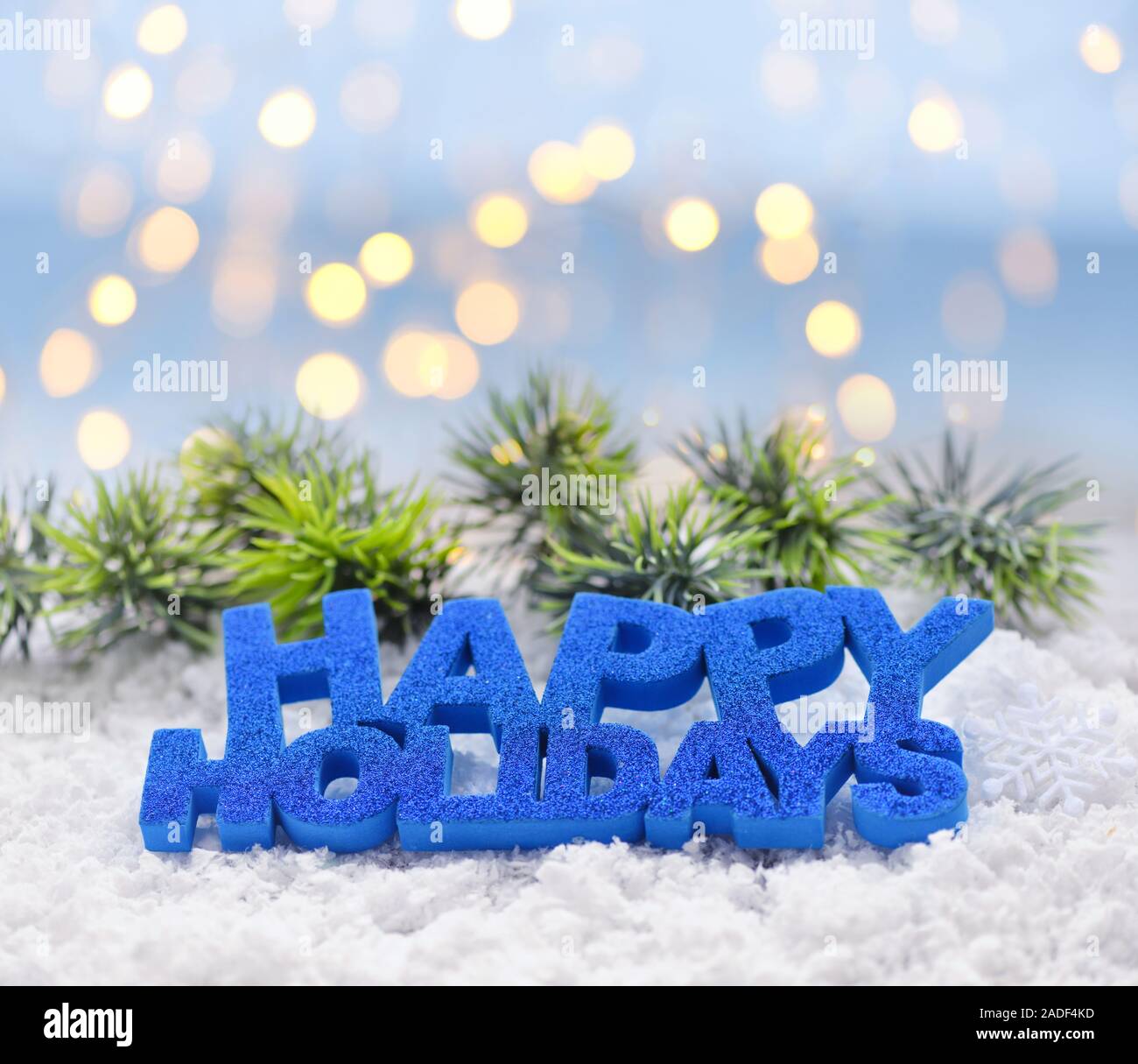 Saluto "Happy Holidays' sulla neve sullo sfondo di luci festive. Natale o Capodanno saluto il card. Foto Stock