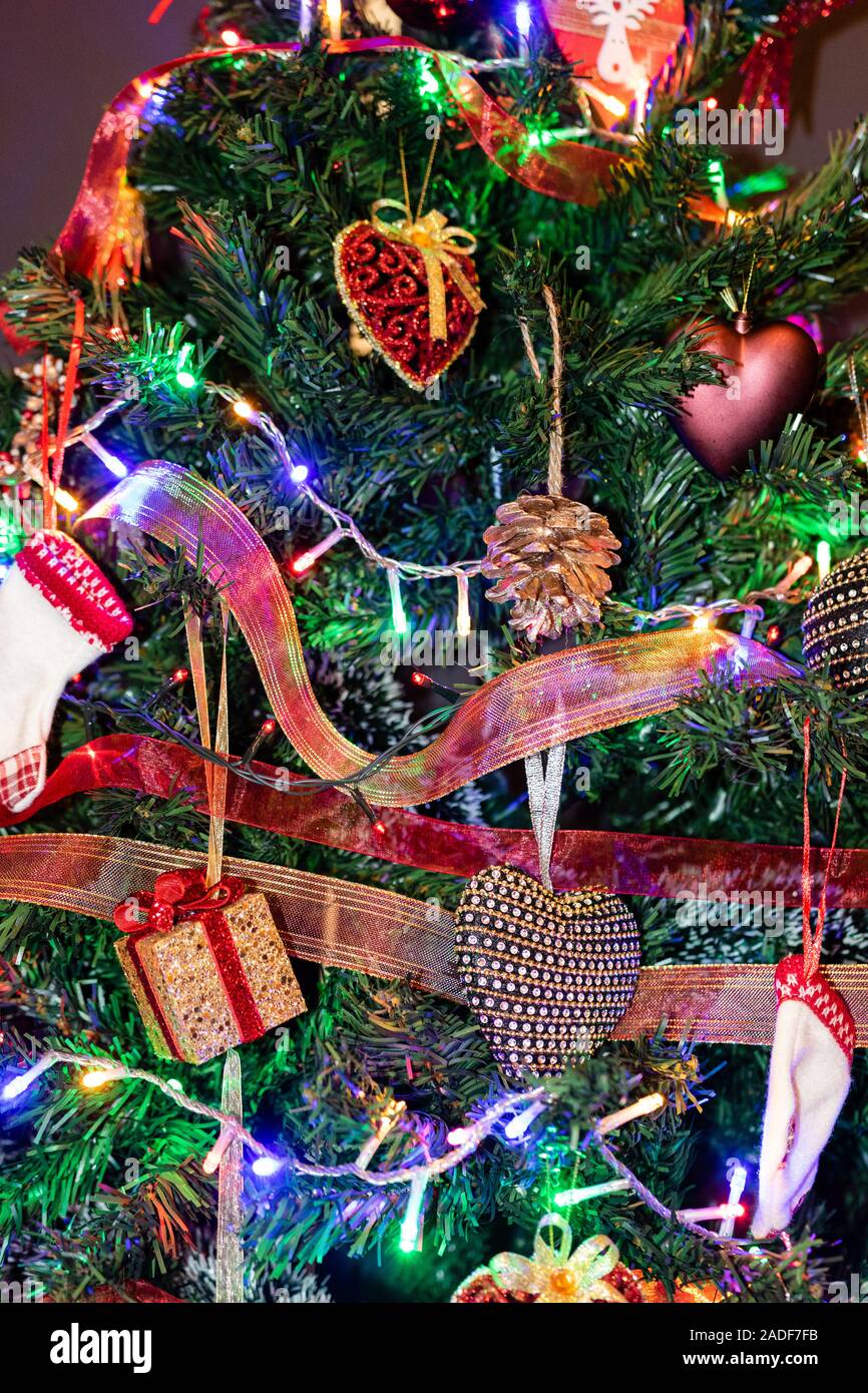 Natale decorazioni pensili in abete. Albero di Natale decorato. Ramo di abete con decorazioni di Natale circondato da luci e ghirlande. Foto Stock