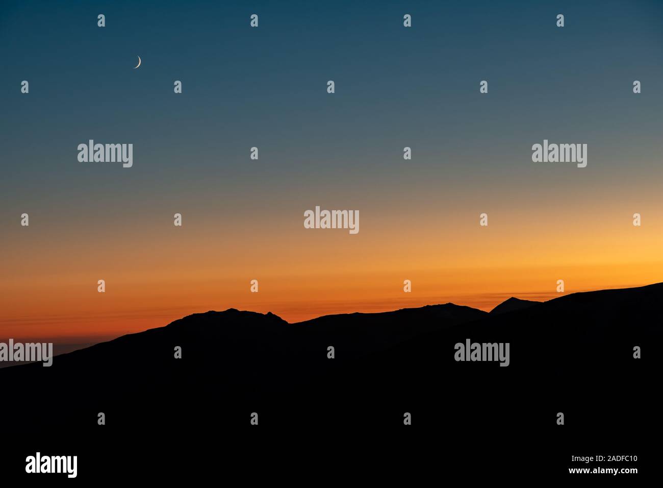 Crescent Moon Rising oltre il paesaggio di montagna Foto Stock