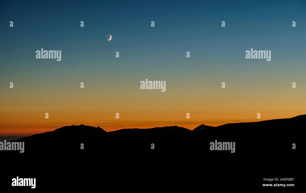 Crescent Moon Rising oltre il paesaggio di montagna Foto Stock