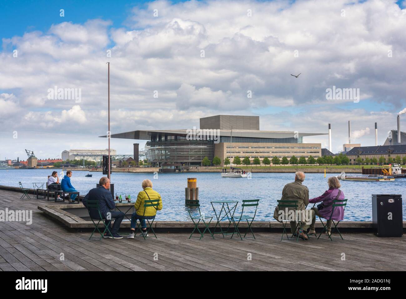 La città di Copenhagen, vista della coppia di turisti seduti sul Playhouse Theatre terrazza e guardare al di là del porto alla Opera House di Copenhagen, Danimarca. Foto Stock