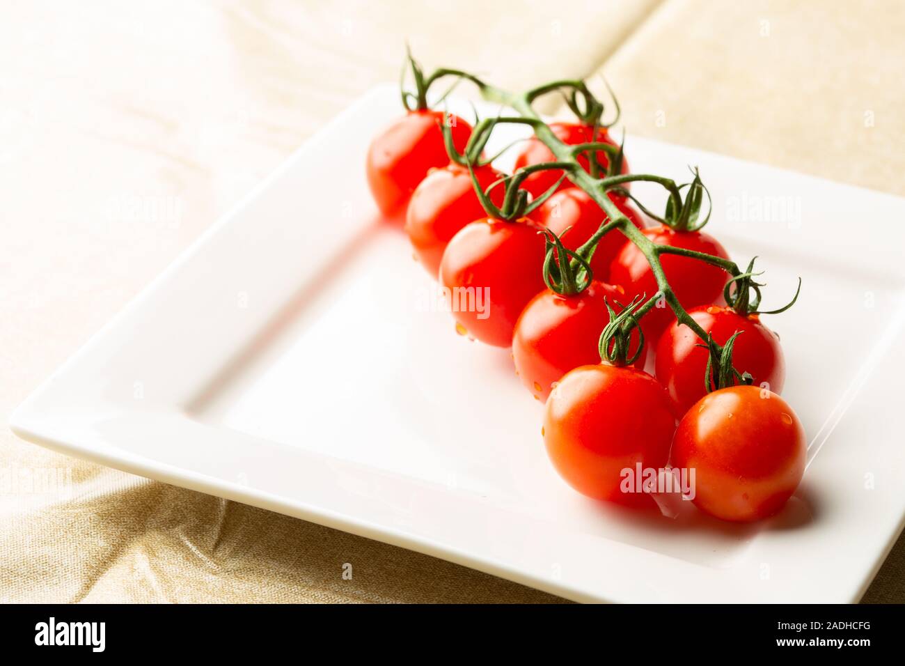 Ramo di pomodori ciliegia sulla piastra quadrata Foto Stock