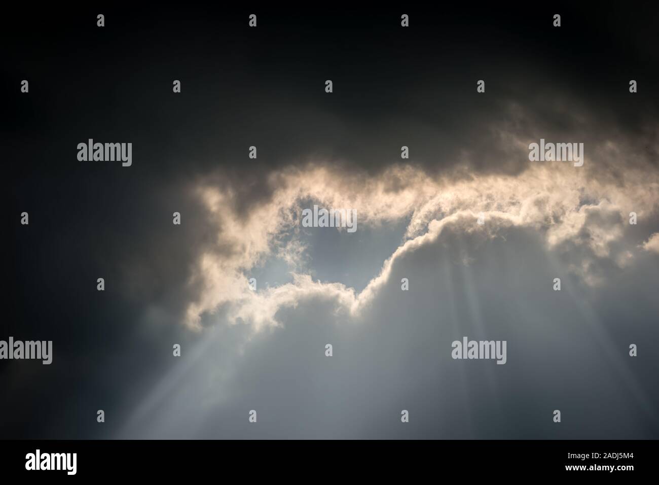 Una insolita formazione delle nuvole scure nuvole temporalesche incontro luce, un argento brillante rivestimento come il sole splende attraverso uno spazio Foto Stock