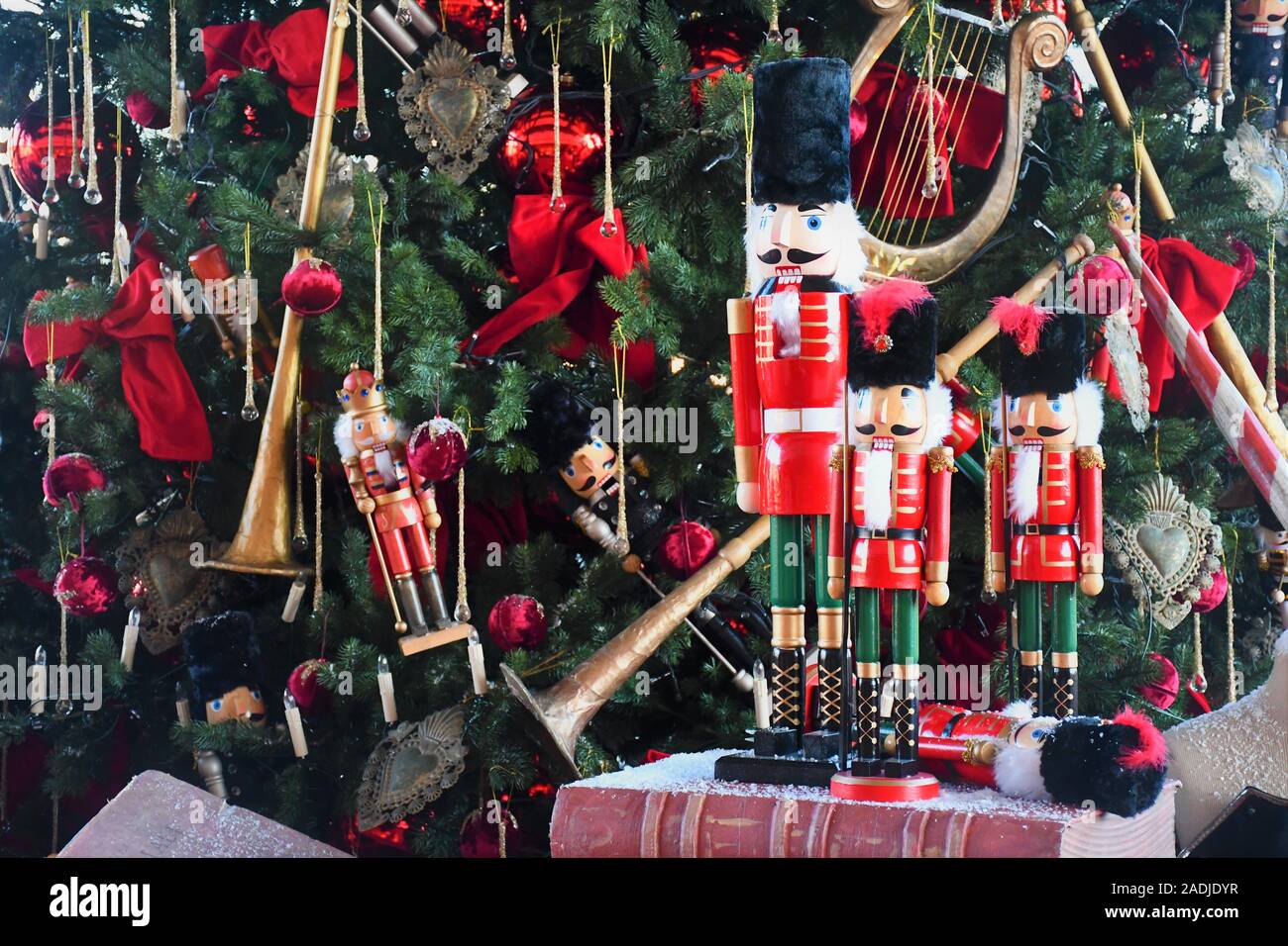 Soldato schiaccianoci statua in legno in piedi di fronte ad albero di Natale decorato su un vecchio libro Foto Stock