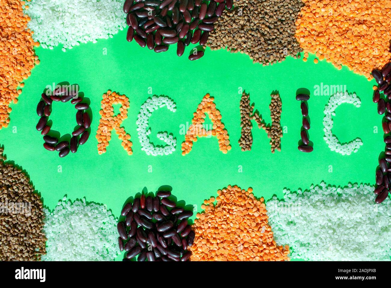 Telaio di diversi cereali con parola organico su sfondo verde. Parola organico fatto di grano vari. Mix di cereali e fagioli. Alimenti biologici. Foto Stock
