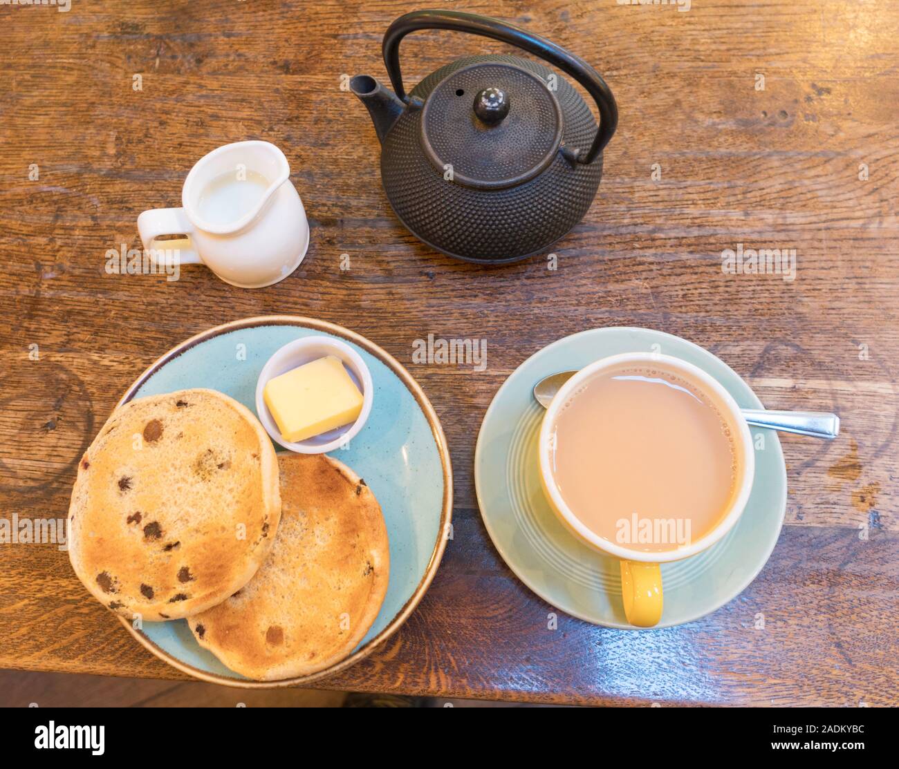 Una tazza di tè e un teacake tostato con teiera e bricco per latte, England, Regno Unito Foto Stock