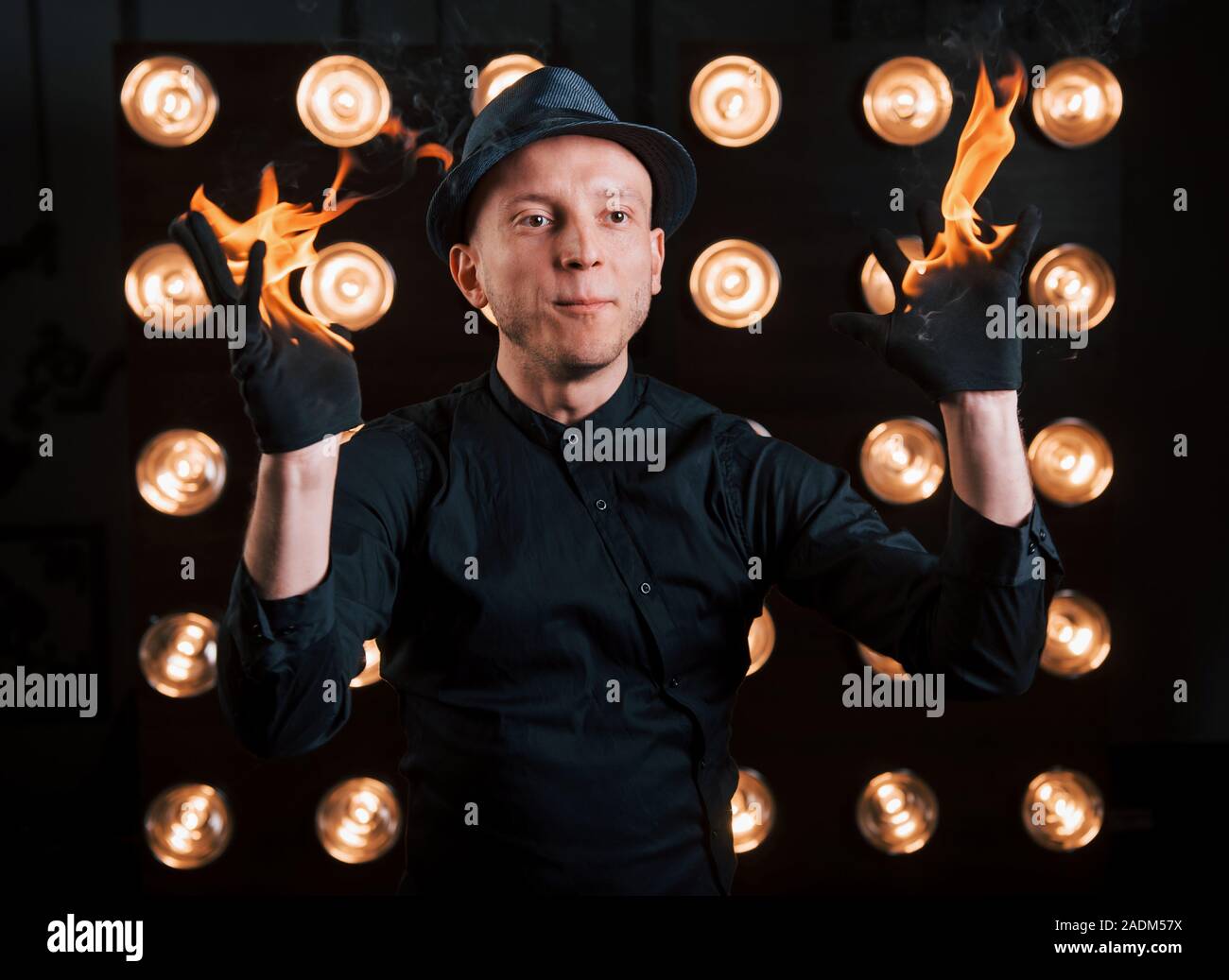 Professional illusionista in black hat, camicia e glowes giocando con il fuoco Foto Stock
