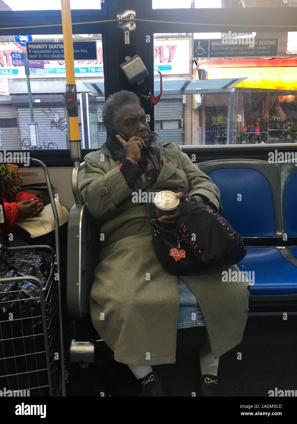I vecchi Caraibi donna a cavallo di un autobus in Brooklyn, parlando sul suo telefono cellulare. Foto Stock