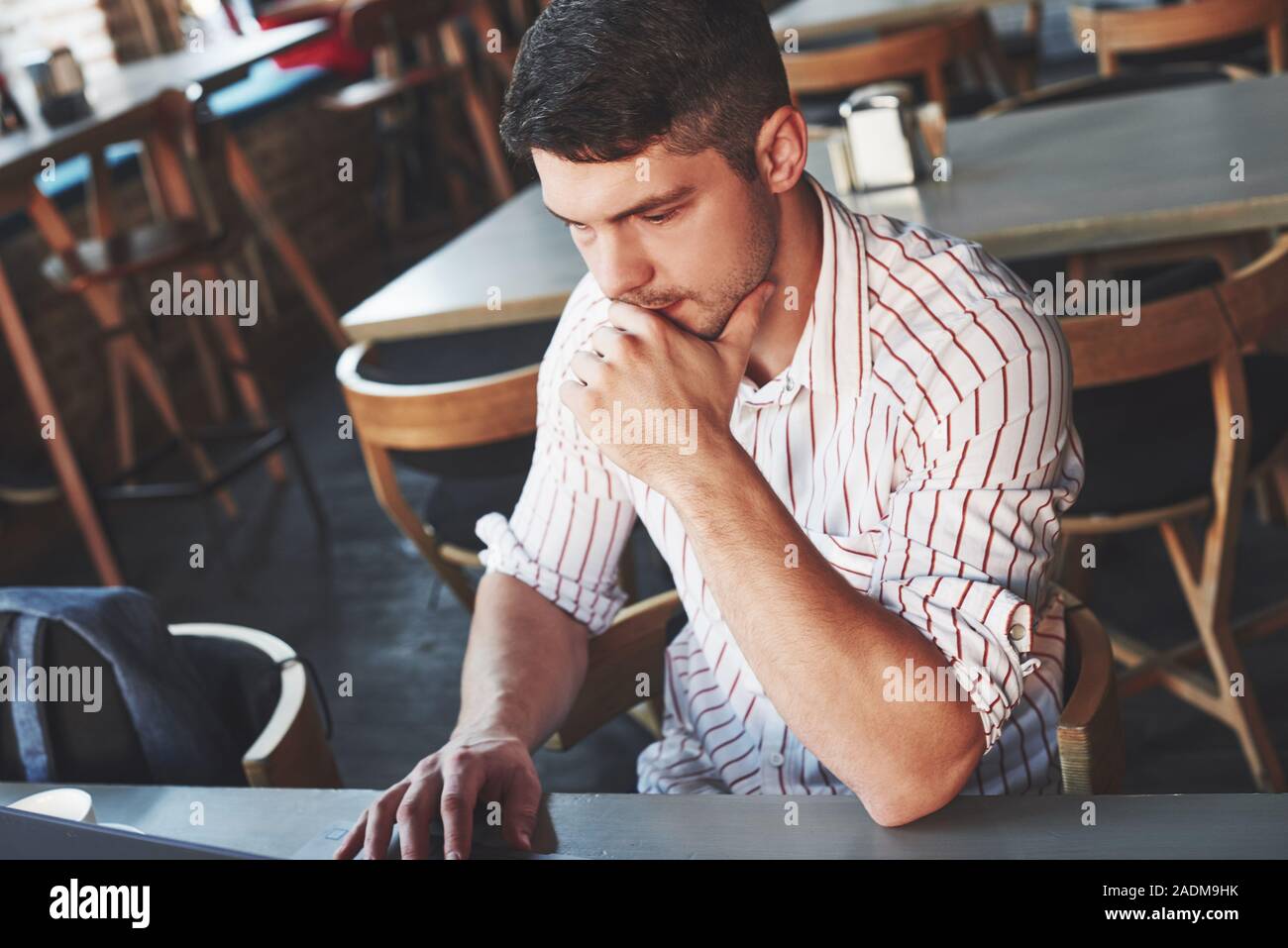 Look concentrato. Uomo adulto si siede nel cafe di giorno e di utilizzare il computer portatile per il lavoro a distanza Foto Stock