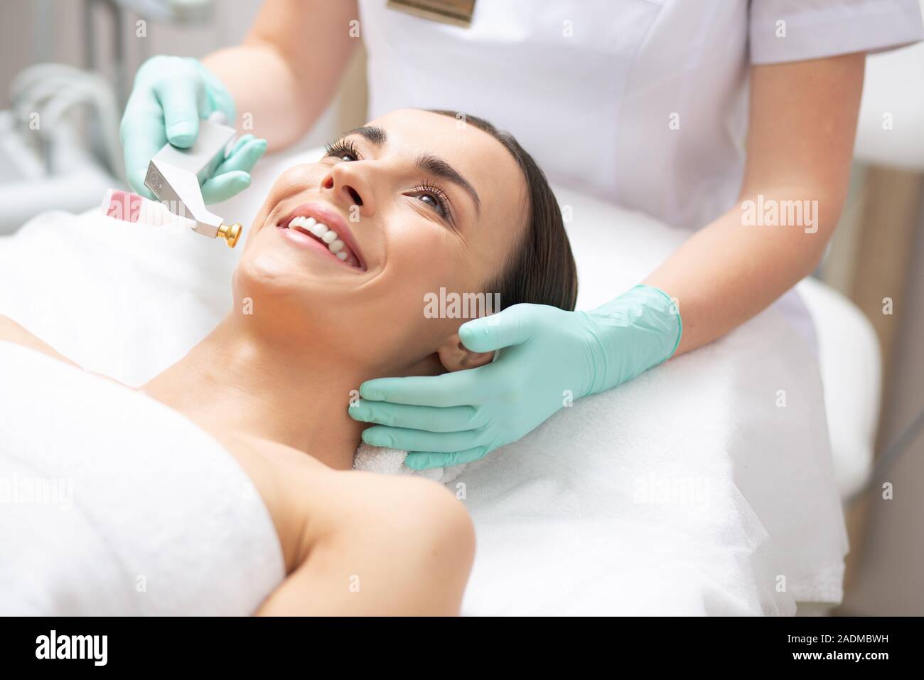 Volto di donna felice e dermatologo tenendo l'attrezzo metallico Foto Stock