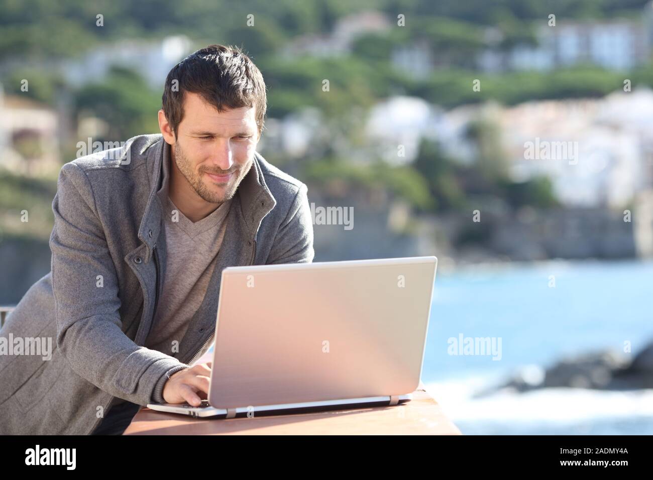 Grave un uomo che sta utilizzando un computer portatile in un balcone in inverno sulla spiaggia Foto Stock