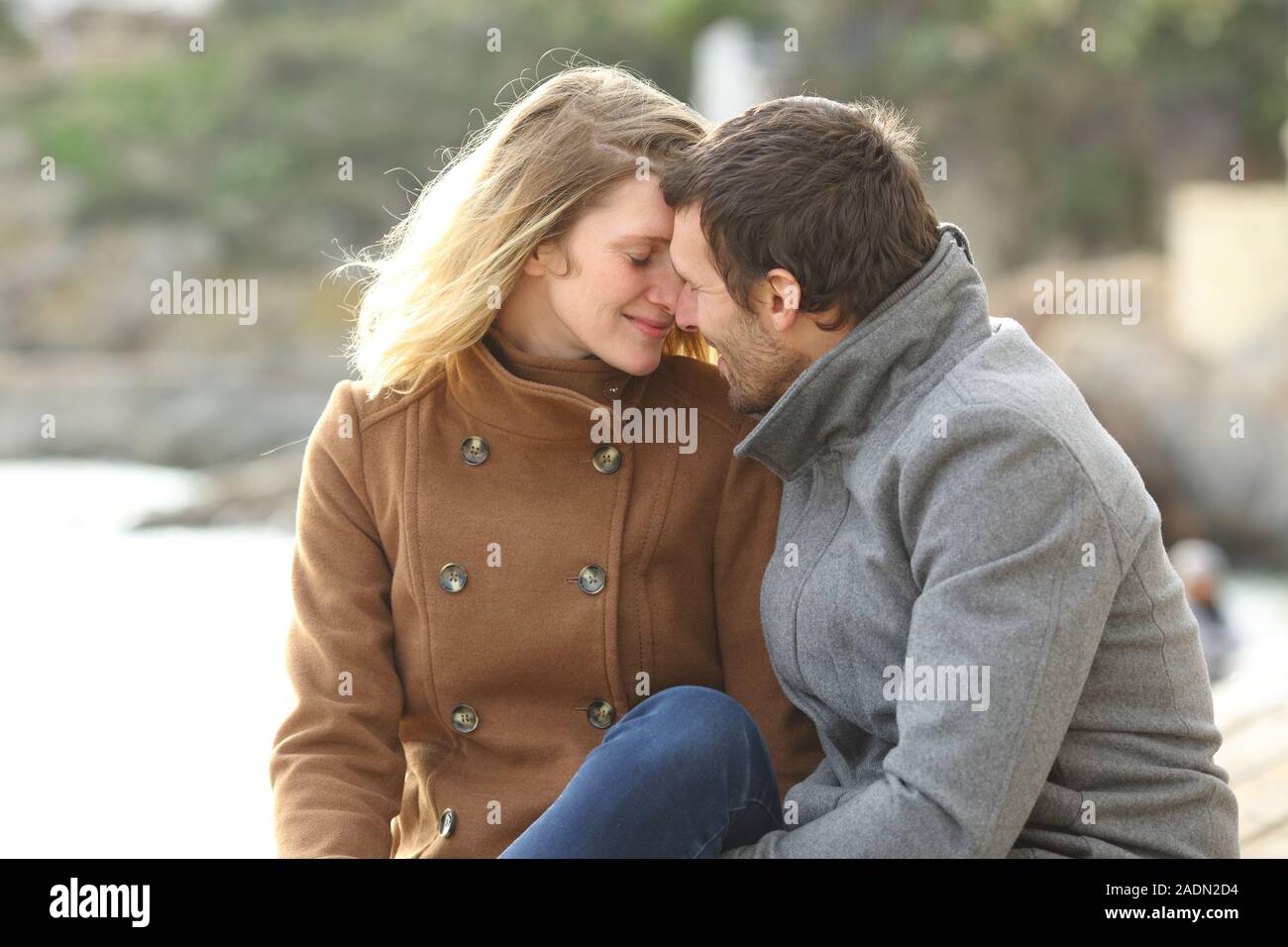 Adulto Giovane in amore flirt seduto sulla spiaggia in vacanze invernali Foto Stock