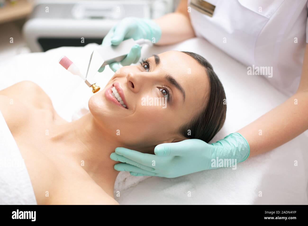 Mano del dermatologo toccando il volto di donna sorridente Foto Stock