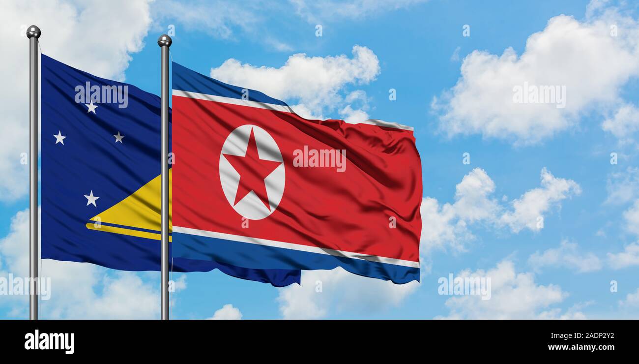 Tokelau e Corea del Nord bandiera sventolare nel vento contro bianco torbido cielo blu insieme. Concetto di Diplomazia e relazioni internazionali. Foto Stock