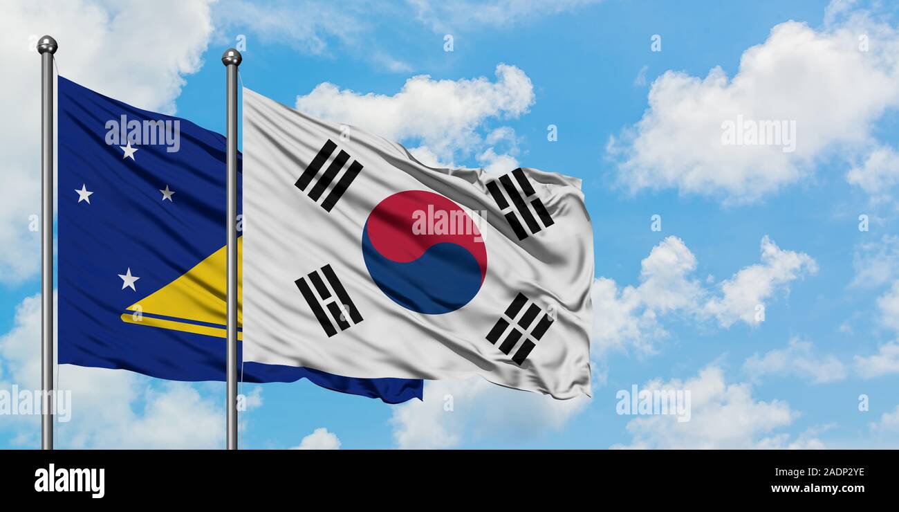 Tokelau e Corea del Sud bandiera sventolare nel vento contro bianco torbido cielo blu insieme. Concetto di Diplomazia e relazioni internazionali. Foto Stock