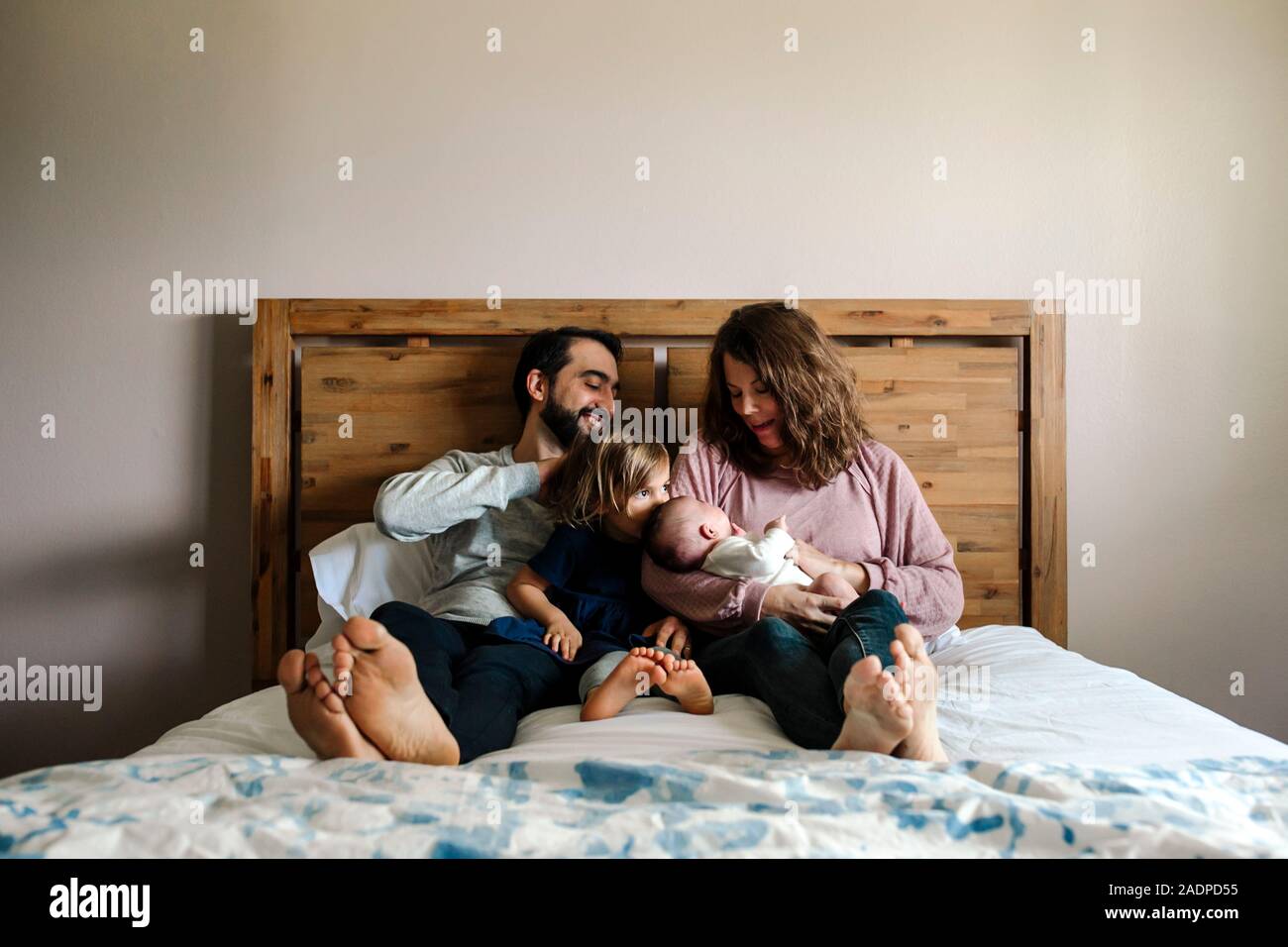 Famiglia con neonati e 4 anni ragazze coccolare insieme sul letto Foto Stock