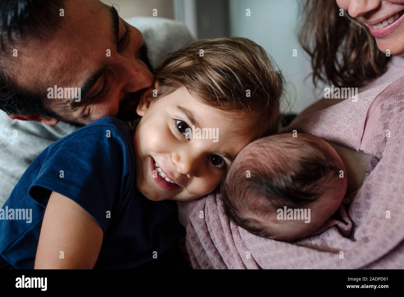Ragazza sorridente coccolati tra mamma, papà e gemelli del neonato Foto Stock