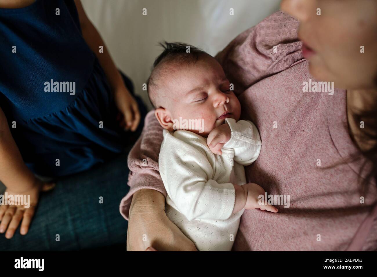Madre indossa maglia rosa amorevolmente detiene il neonato Foto Stock