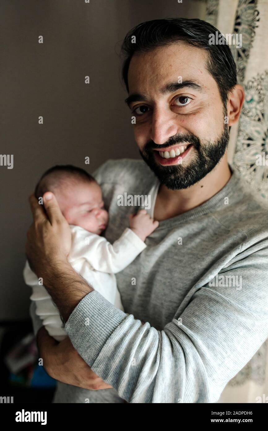 Orgoglioso padre sorridente con la barba holding neonato Foto Stock