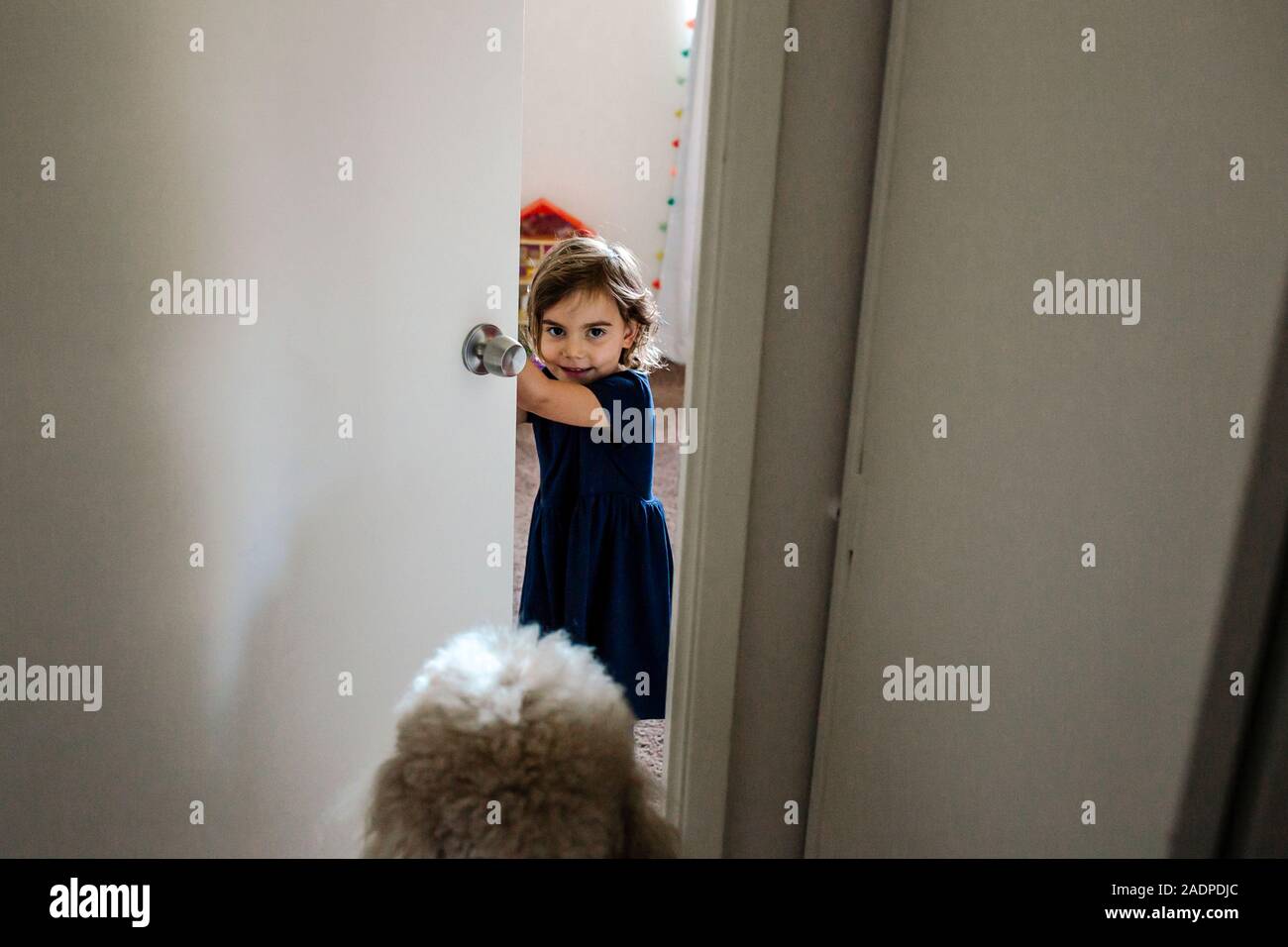 4 yr old girl guardando fuori attraverso la porta della camera da letto Foto Stock