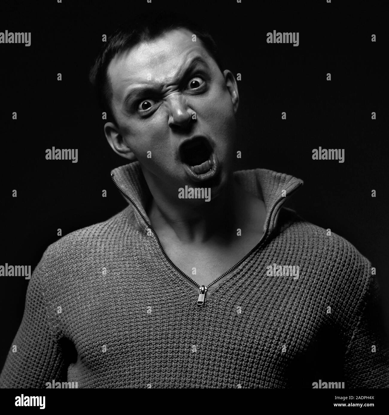 Angry Man zombie guardando con occhi aggressivi e ampia bocca aperta. Closeup attore emozione ritratto. In bianco e nero Foto Stock