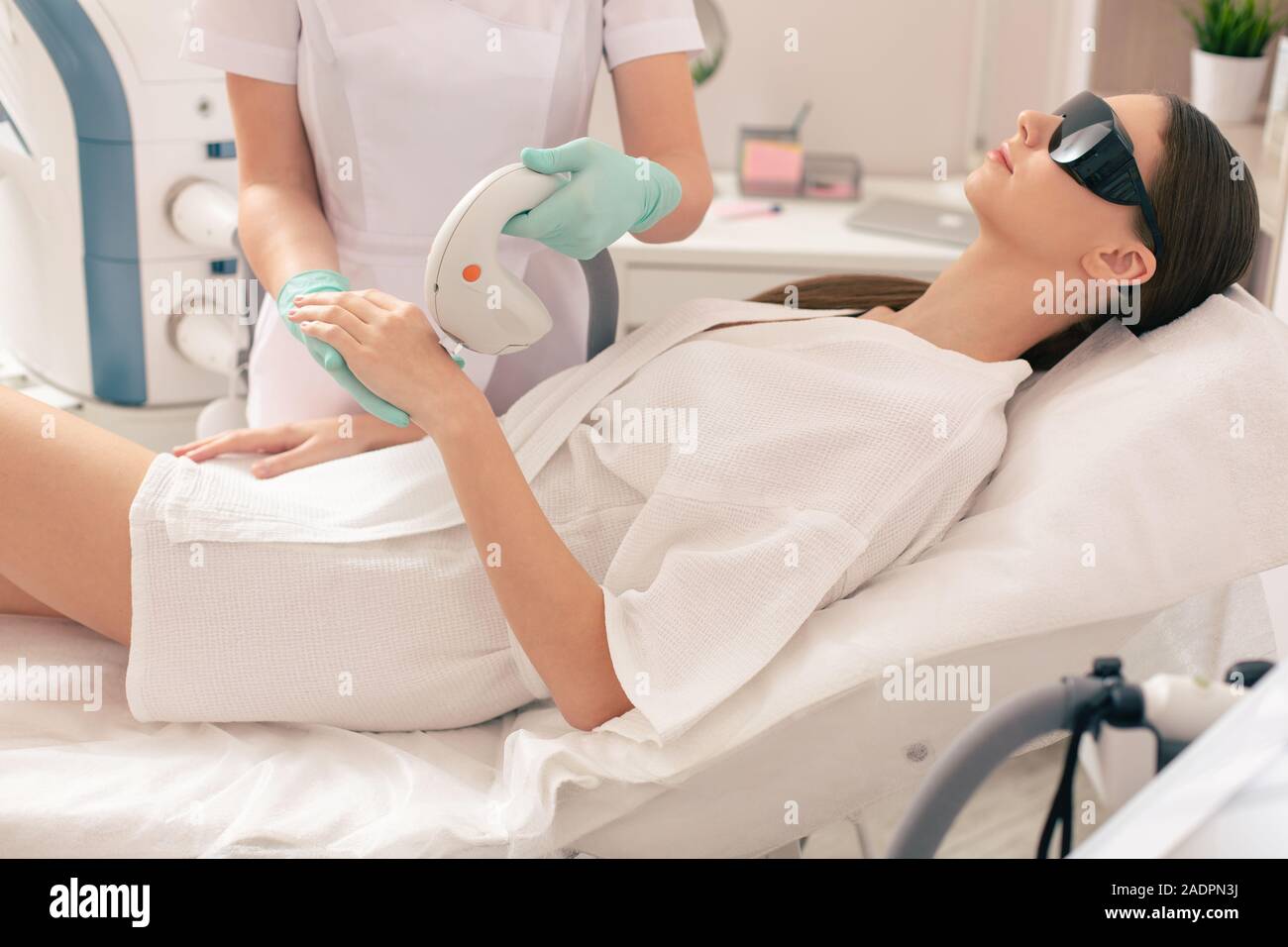 Donna in accappatoio in fase di rimozione dei capelli del laser Foto Stock