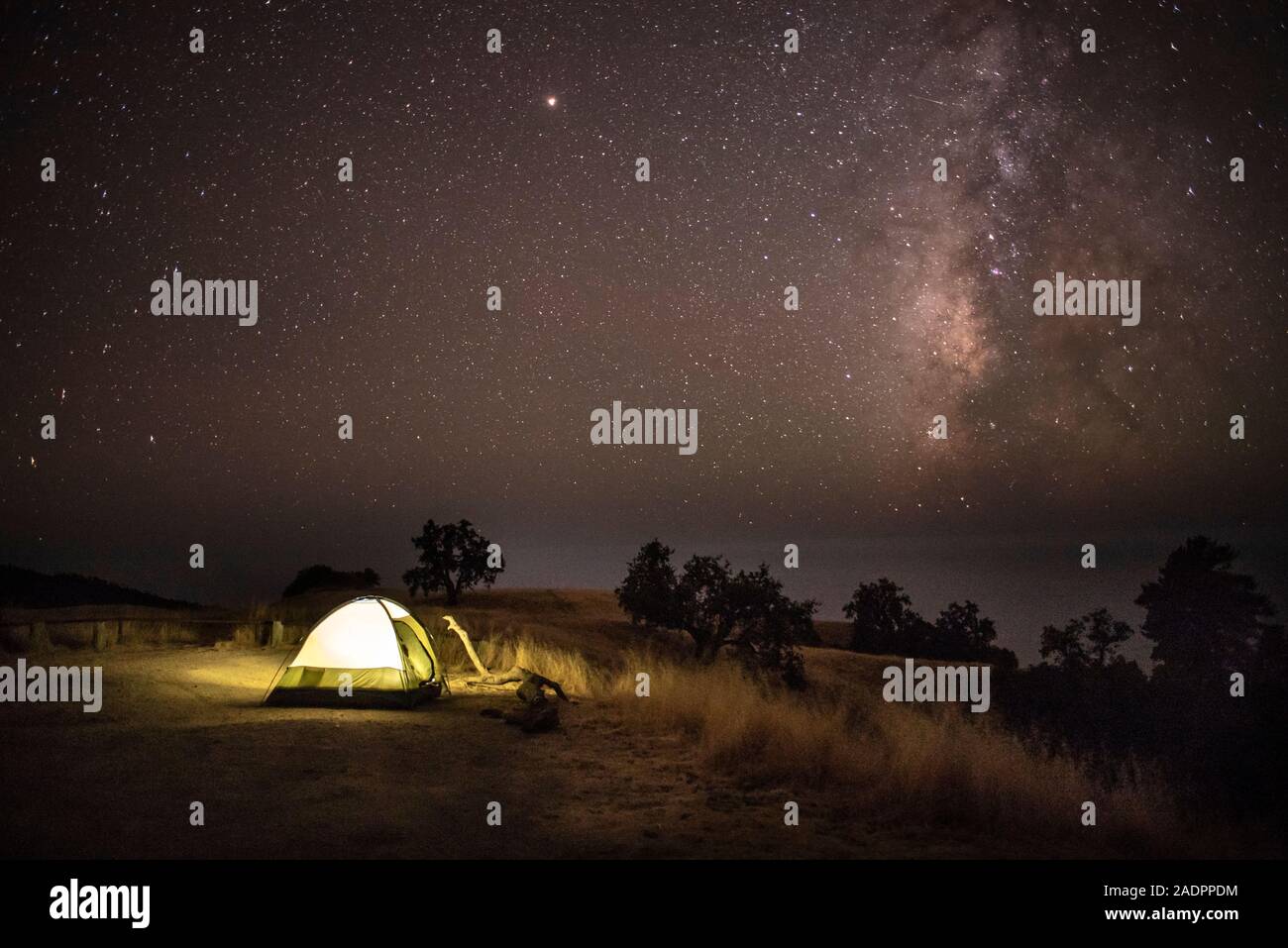 Il campeggio spettacolare mostra la tenda illuminata sotto il cielo notturno pieno di stelle e la Via Lattea galassia Foto Stock