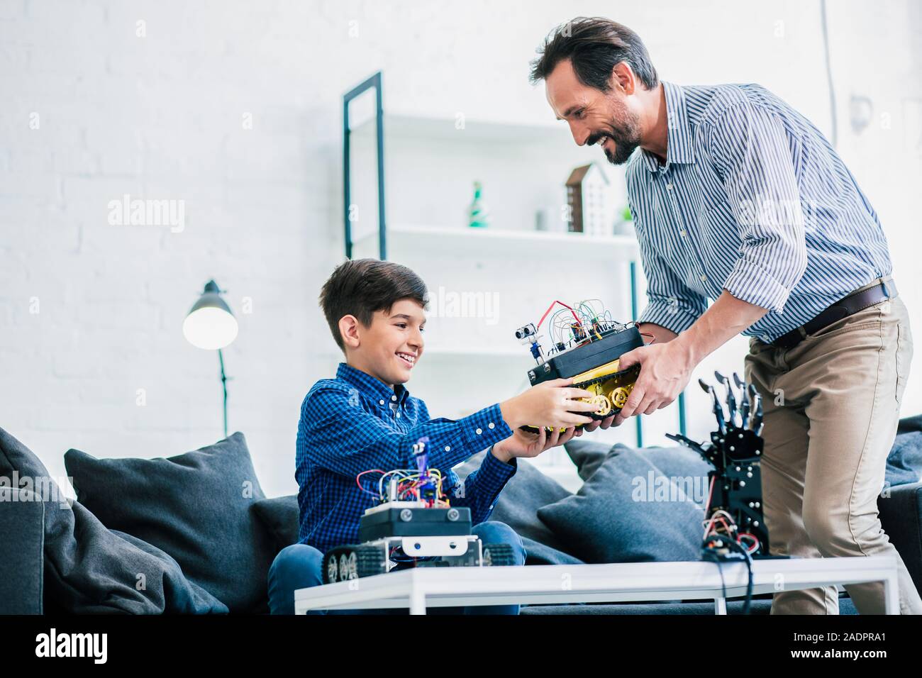 Padre gioioso e suo figlio tenendo un dispositivo robotico Foto Stock