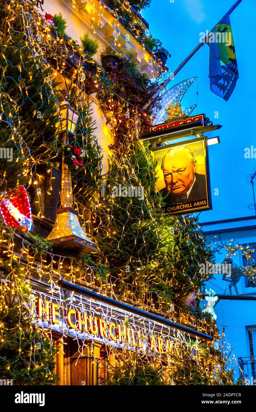Opulente luci e decorazioni natalizie sulla facciata del Churchill Arms Pub, Londra, Regno Unito Foto Stock