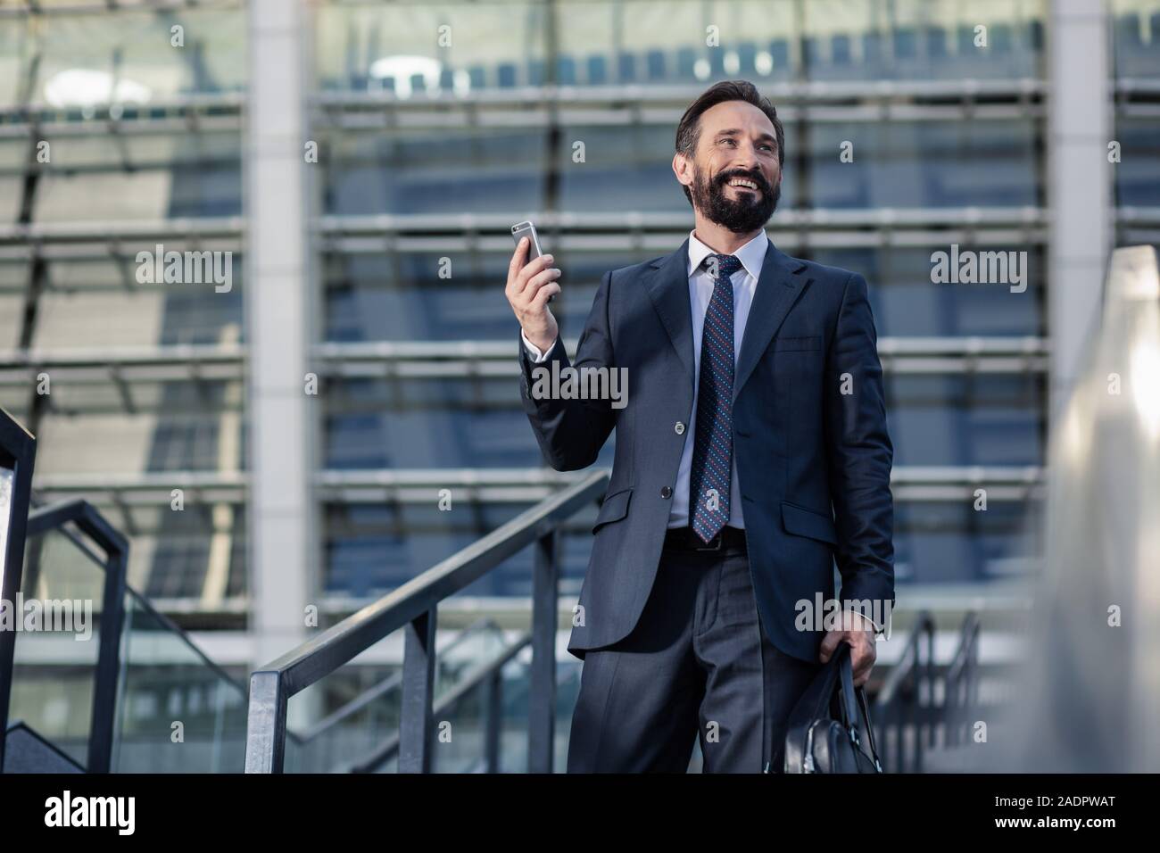 Jouful barbuto imprenditore ricevendo una chiamata telefonica Foto Stock