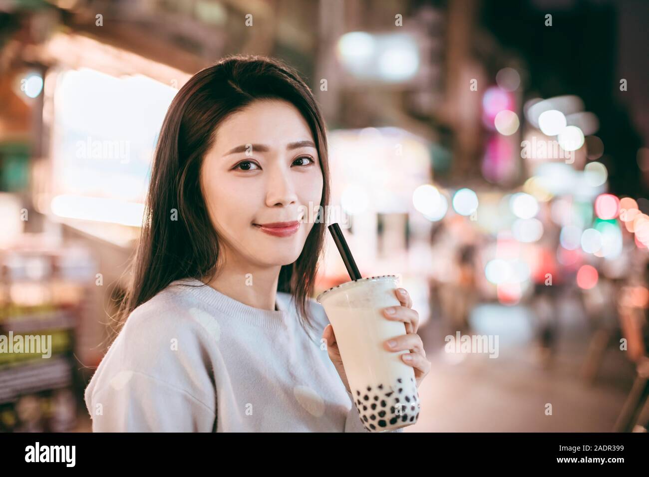 Donna asiatica gustare latte bolla tè con cibo di strada nella notte di mercato Foto Stock