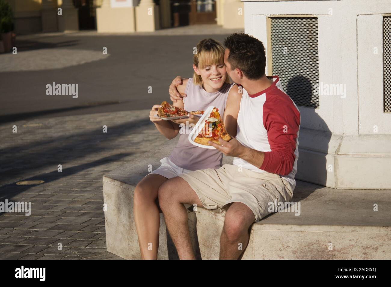 Junges Paar isst eine Pizzaschnitte - Coppia giovane mangiare la pizza all'aperto Foto Stock