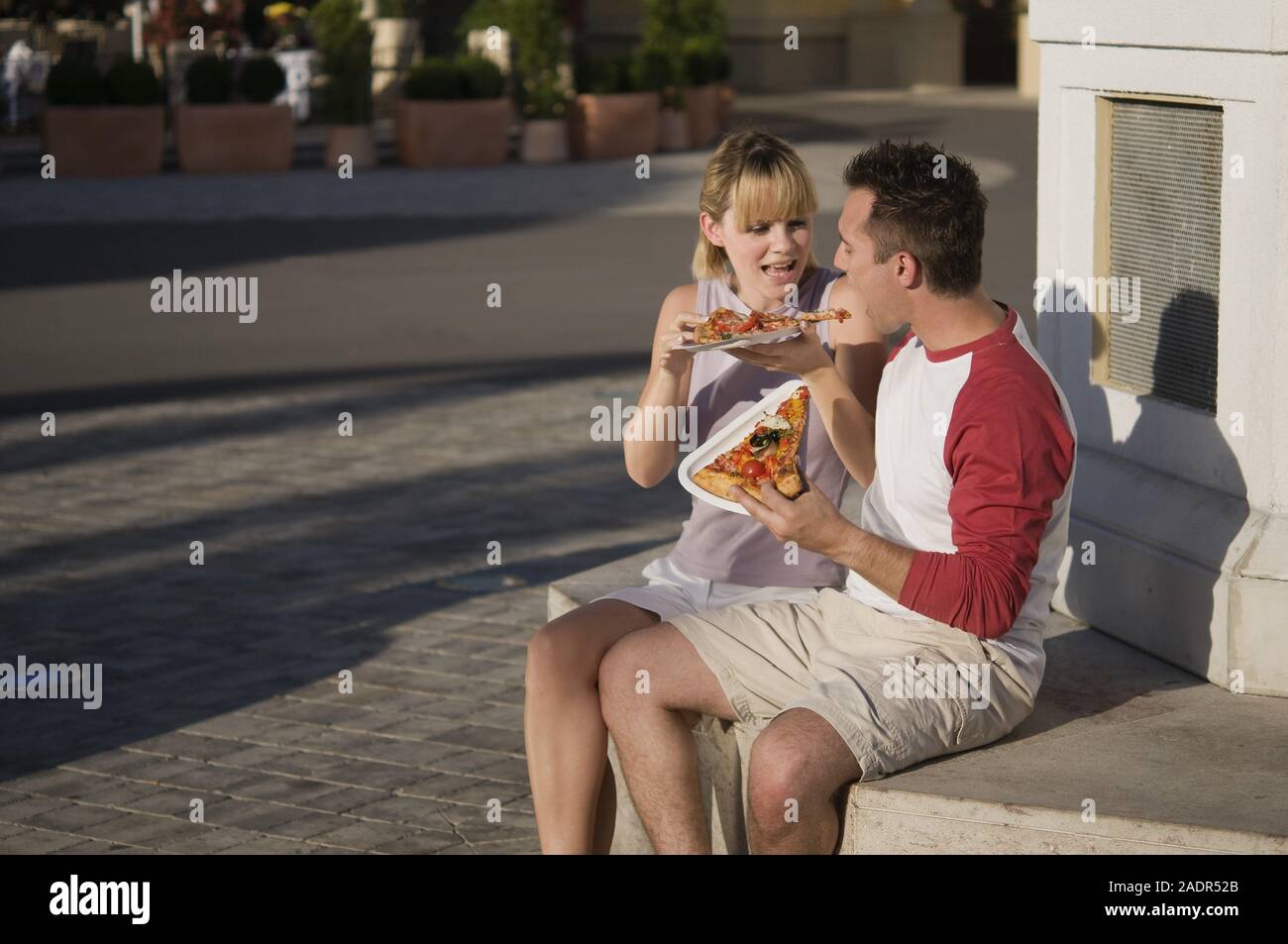 Junges Paar isst eine Pizzaschnitte - Coppia giovane mangiare la pizza all'aperto Foto Stock
