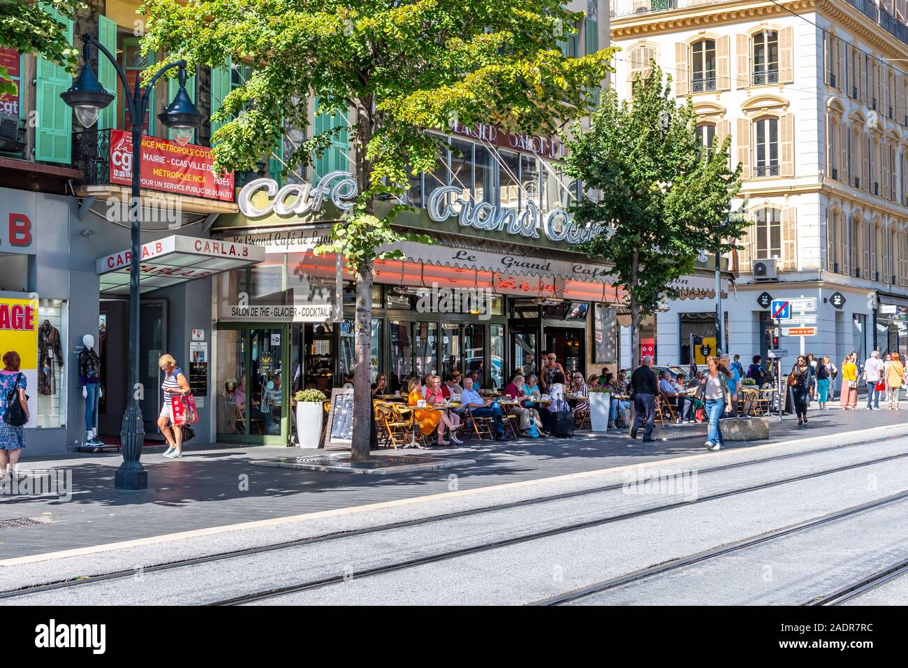 Il francese la gente del posto e i turisti godetevi un pomeriggio pasto presso un cafè sul marciapiede di Nizza, Francia. Foto Stock